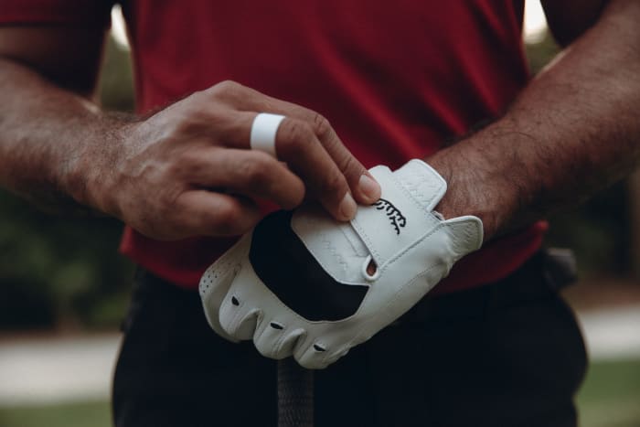 Tiger Woods models a white Sun Day Red golf glove.